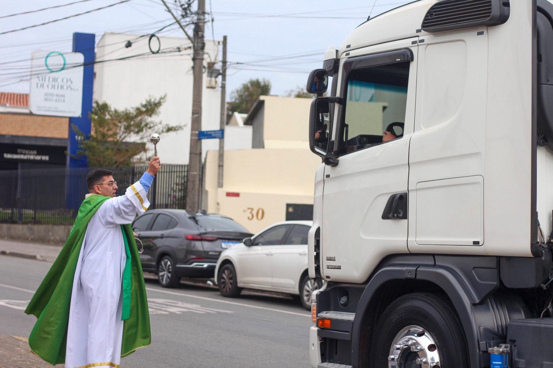 Padre abençoando um caminhão durante a carreata da Festa do Carmo, no Boqueirão